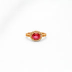 Gold ring with a red gemstone on a white background